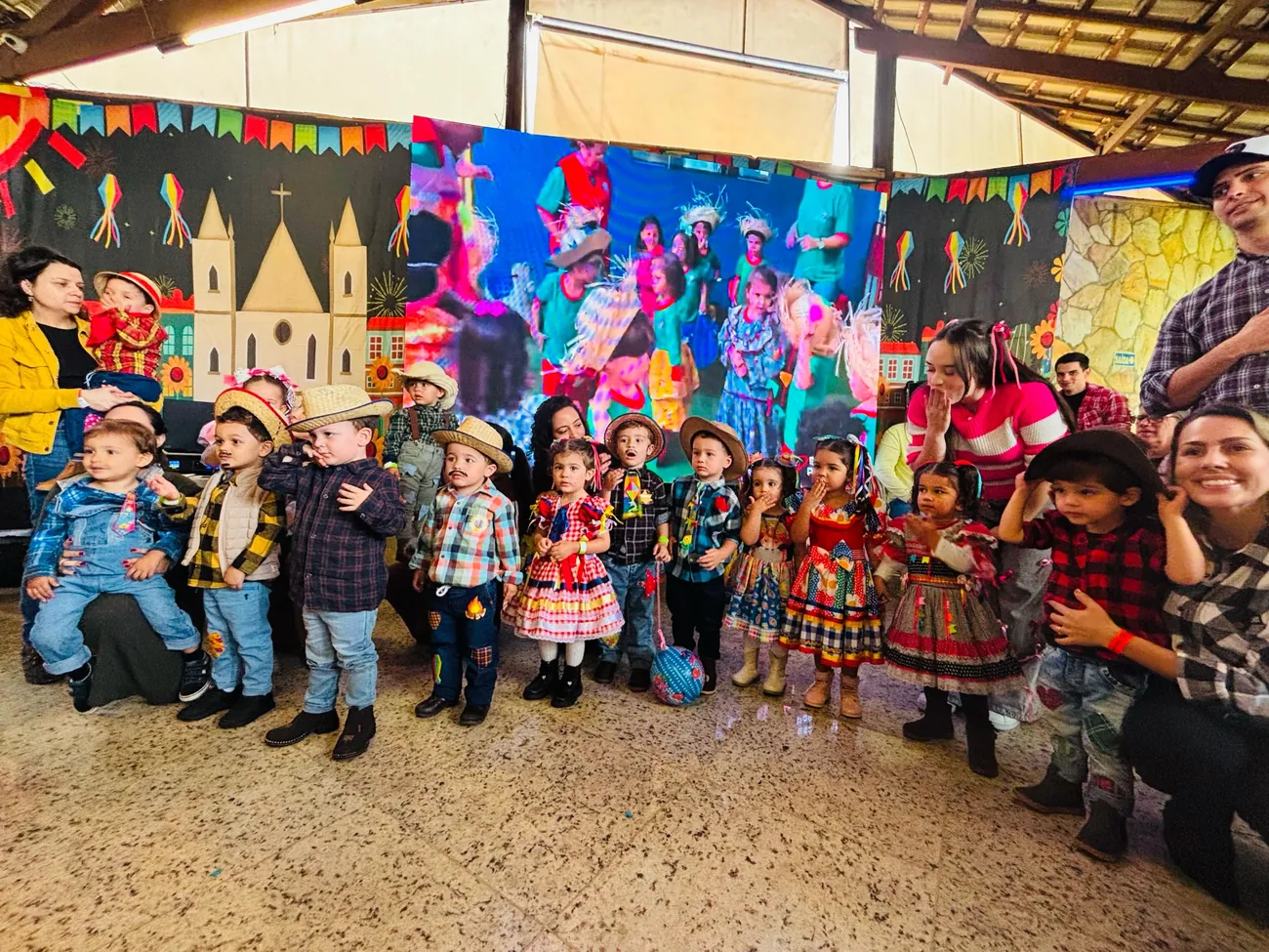 Crianças de chapéu de palha e roupa caipira posando juntas no Arraiá da escola